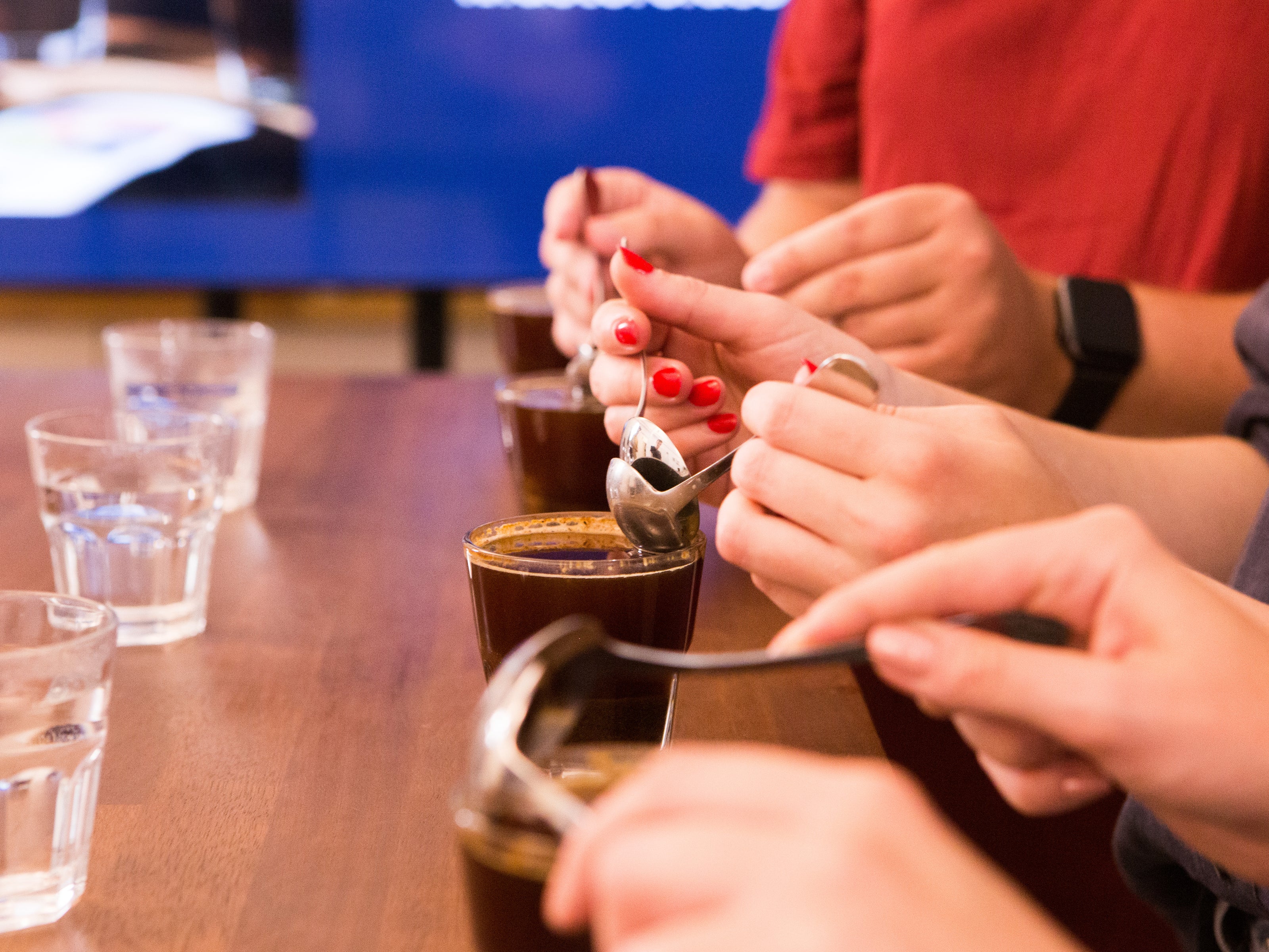A group of people cupping coffee using cupping spoons.